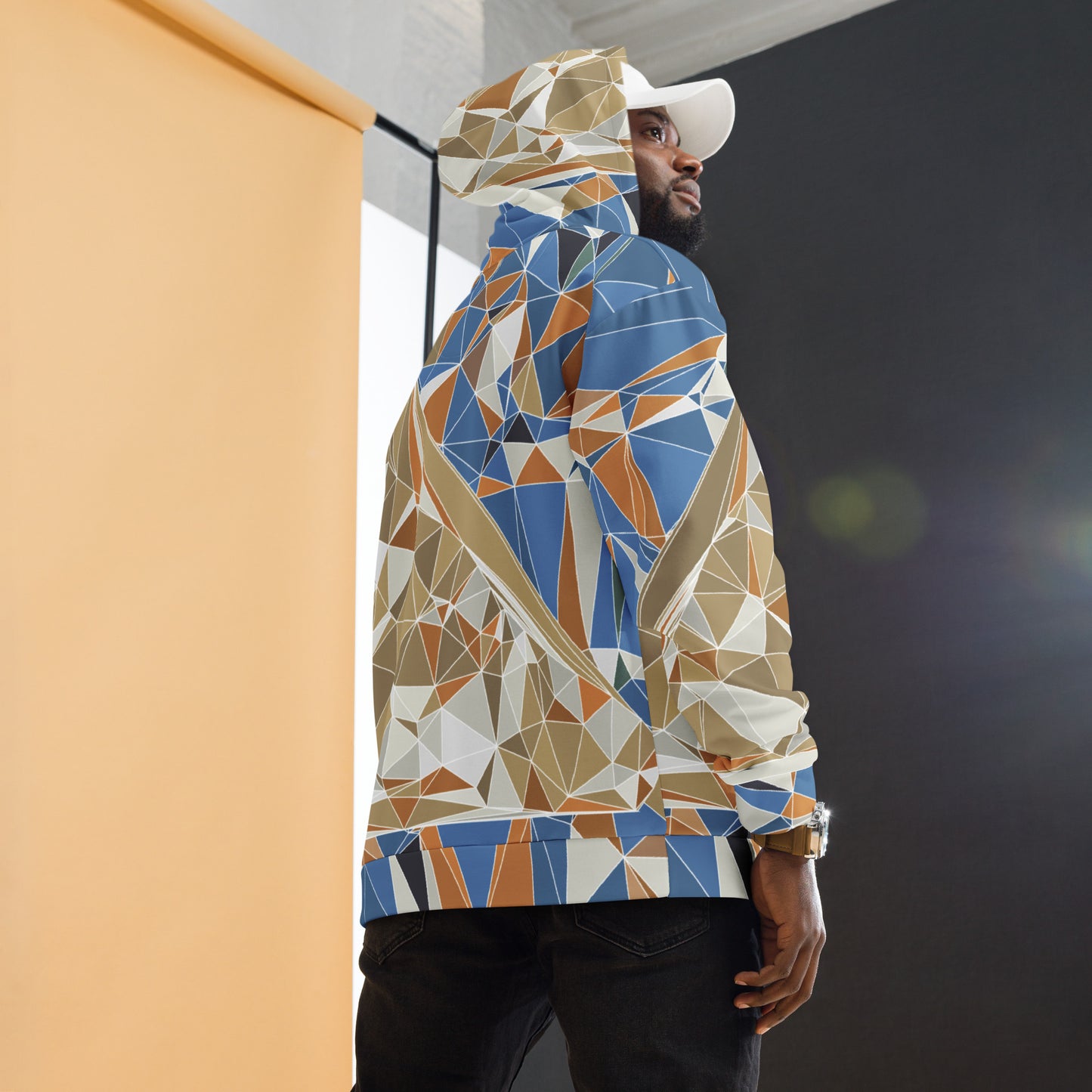 Person wearing a colorful geometric-patterned Mount Fuji hoodie with a white cap indoors.