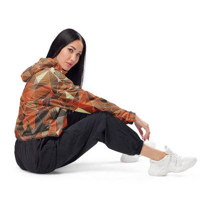 Woman wearing a cropped multicolor geometric patterned windbreaker jacket and black pants sitting on a white background
