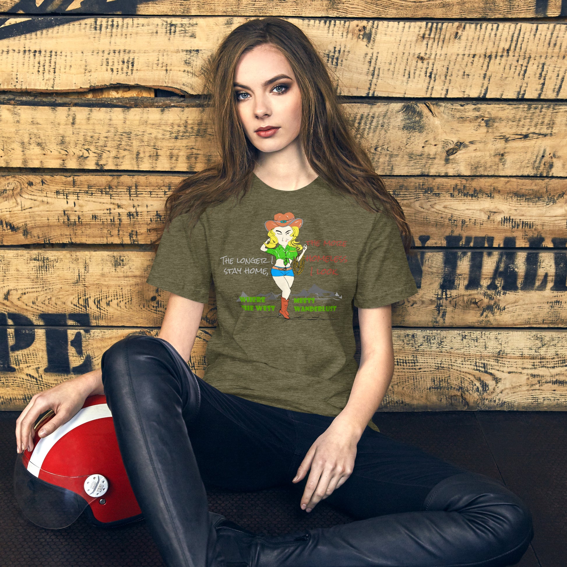 Woman wearing a green t-shirt with a playful cowgirl graphic design and text, sitting against a wooden wall.