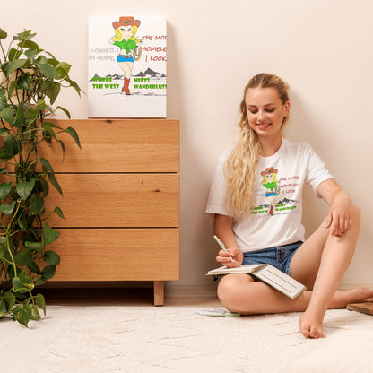 Woman wearing a white T-Shirt with a playful cowgirl graphic design and text, sitting on the floor reading a book with a plant and wooden dresser in the background